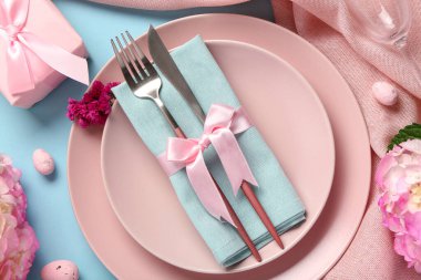 Mavi arka planda Paskalya yumurtaları ve ortancalarla güzel bir masa.