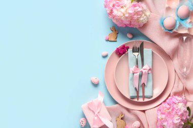 Mavi arka planda Paskalya yumurtaları ve ortancalarla güzel bir masa.