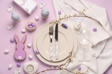 Paskalya yumurtaları ve leylak arkaplanda şarap kadehiyle güzel bir masa.