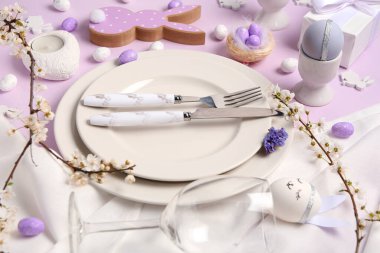 Paskalya yumurtaları ve şarap kadehiyle leylak arka planda güzel bir masa, yakın plan.