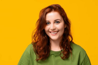 Sarı arka planda gülümseyen kızıl saçlı kadın.