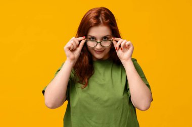 Sarı arka planda gözlüklü güzel kızıl saçlı kadın.