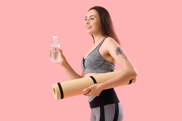 Sportig Ung Kvinna Med Flaska Vatten Och Träningsmatta Rosa Bakgrund — Stockfoto