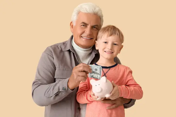 Menino Com Seu Avô Colocando Dinheiro Mealheiro Fundo Bege — Fotografia de Stock