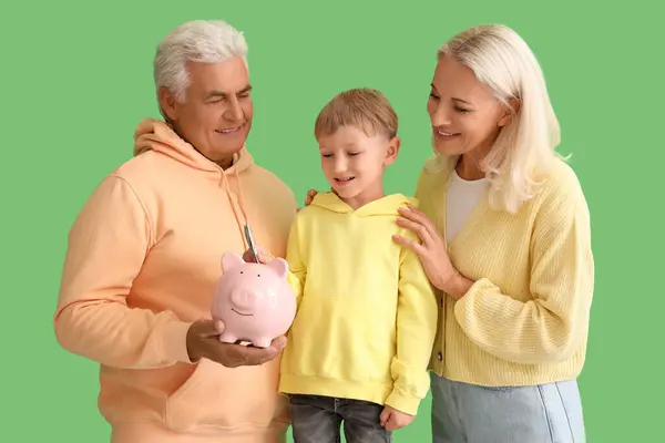 Menino Com Seus Avós Colocando Dinheiro Mealheiro Fundo Verde — Fotografia de Stock
