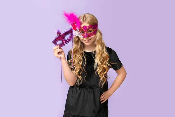 在紫丁香背景上戴着狂欢节面具的小女孩真有趣 — 图库照片