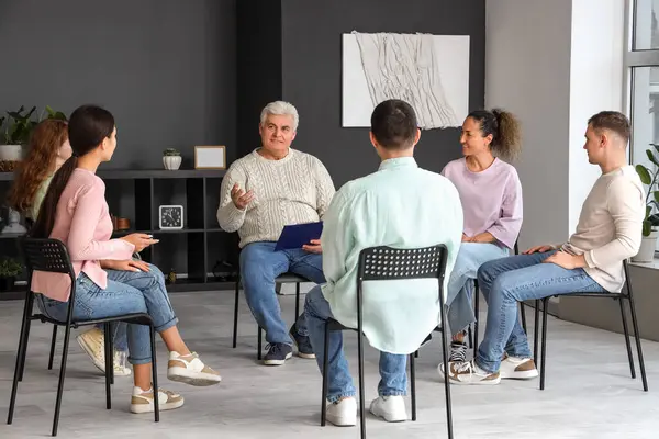 Mature psychologist talking at group therapy session