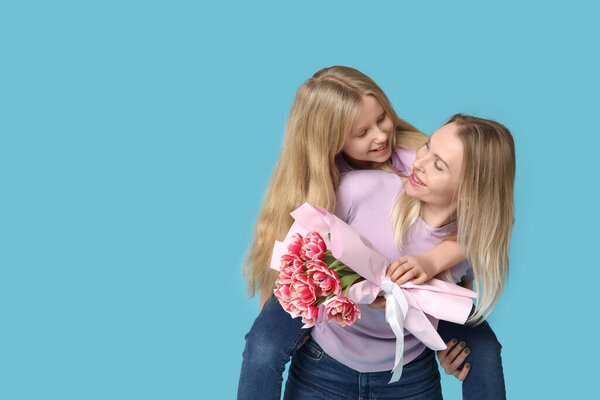 Милая маленькая девочка со своей мамой и букет на День матери на синем фоне