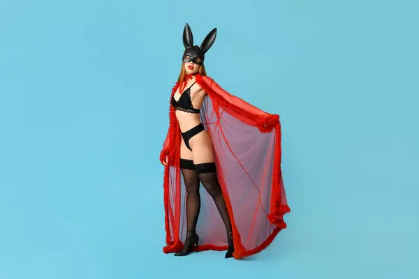 Sexy young woman in bunny mask on blue background. Easter celebration