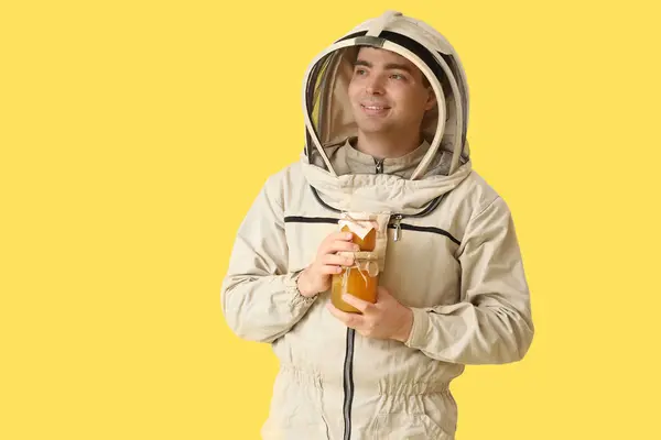 带有黄色背景蜂蜜瓶的男性养蜂人 — 图库照片