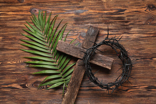 Crown of thorns with cross and palm leaf on wooden background. Good Friday concept