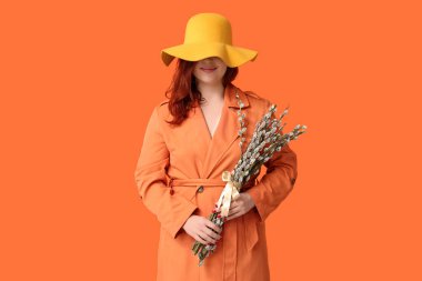 Beautiful young woman with pussy willow branches on orange background. Easter celebration