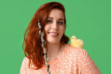 Beautiful young woman with pussy willow branch and chick on green background. Easter celebration