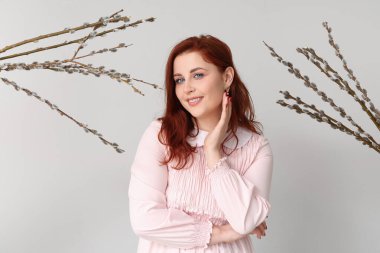 Beautiful young woman and pussy willow branches on grey background. Easter celebration