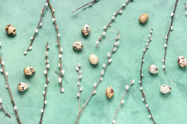 Pussy willow branches and Easter eggs on green background