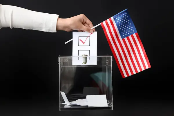 stock image Voting woman with flag of USA near ballot box on black background