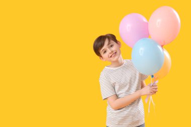 Sarı arka planda balonları olan küçük bir çocuk. Çocuk Bayramı kutlaması