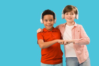 Mavi arka planda kulaklık takan küçük çocuklar. Çocuk Bayramı kutlaması