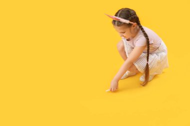 Sarı arka planda tebeşir parçasıyla taç çizen küçük kız. Çocuk Bayramı kutlaması