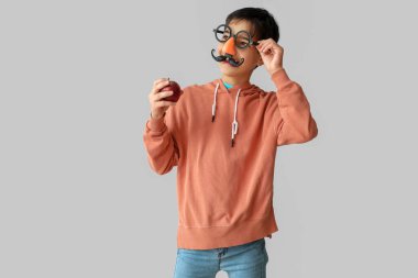 Hafif arka planda elmayla kılık değiştirmiş komik bir çocuk. Çocuk Bayramı kutlaması