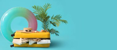 Plaj aksesuarları, giysiler ve mavi arkaplanda şişme yüzük ile bavul metin için boşluk