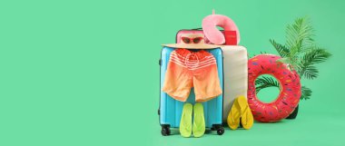 Yeşil zemin üzerinde plaj aksesuarları olan bavullar ve metin için yer