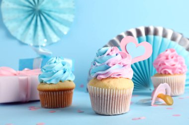 Hediye kutuları, emziği ve dekoru olan lezzetli kekler mavi arka planda. Cinsiyet ortaya çıkan parti kavramı