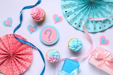 Soru işaretli lezzetli kekler, hediye kutuları ve beyaz arka planda süslemeler. Cinsiyet ortaya çıkan parti kavramı