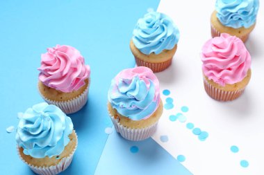 Mavi arka planda konfeti olan lezzetli kekler. Cinsiyet ortaya çıkan parti kavramı