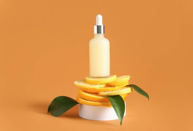 Bir şişe C vitamini ve bej arka planda turunçgil dilimleri.