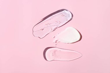 Pembe arka planda kozmetik krem, fırça ve jöle örnekleri