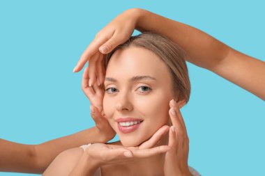 Güzel genç bir kadın ve elleri mavi arka planda.