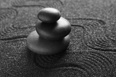 Siyah kumlar üzerinde kaplıca taşları, yakın çekim. Zen kavramı