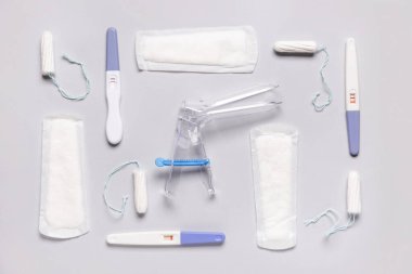 Beyaz arka planda pedli, tamponlu ve hamilelik testli jinekolojik spekulum.