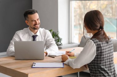 İnsan kaynakları yöneticisi dizüstü bilgisayarla kadın başvuru sahibini ofisinde sorguluyor.