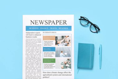 Mavi arka planda defter, kalem ve gözlüklü gazete