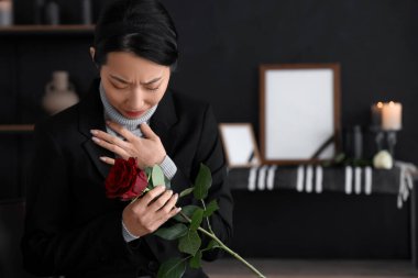 Cenazede elinde gülle yas tutan genç Asyalı kadın.