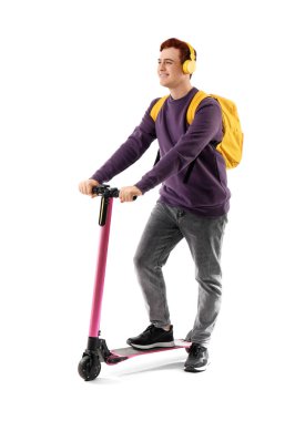 Beyaz arka planda modern elektrikli scooter kullanan kulaklıklı bir erkek öğrenci.