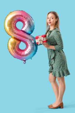 İşitme cihazı olan genç bir kadın balonu 8 şeklinde tutuyor ve mavi arka planda bir hediye. Uluslararası Kadınlar Günü