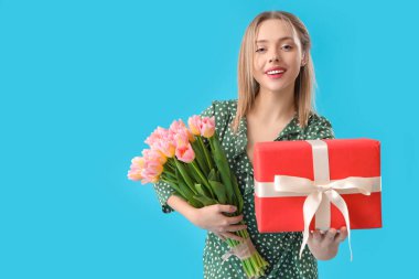 İşitme cihazlı, elinde laleler ve mavi arka planda hediyeler tutan güzel genç bir kadın. Uluslararası Kadınlar Günü