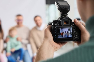 Stüdyoda büyük bir ailenin fotoğrafını çeken erkek fotoğrafçı.