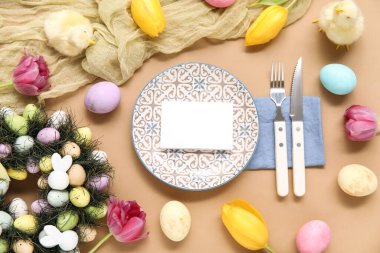 Paskalya kutlaması için kahverengi arkaplanda boş bir kartla şık bir masa ayarı.