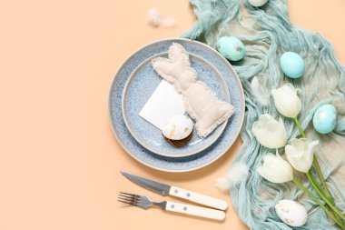 Paskalya kutlaması için bej arkaplanda boş bir kartla şık bir sofra.