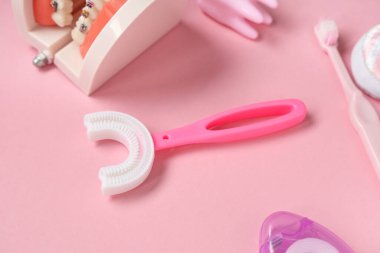 Çene modelli çocuk diş fırçası ve pembe arka planda diş ipi