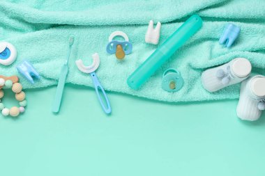 Çocuk diş fırçası, çorap ve turkuaz arka planda emzik içeren havlular.
