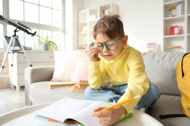 Gözlüklü şirin çocuk evde ödev yapıyor.