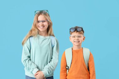 Mavi arka planda gözlüklü sevimli küçük öğrenciler.