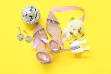 Şık topuklu kağıt taç, disko topu, küpeler ve sarı arka planda güzel çiçekler. Balo konsepti