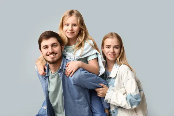 Happy family in stylish denim clothes having fun together on grey background
