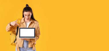 Dizüstü bilgisayarı olan güzel bir kız öğrencinin portresi. Renk arkaplanı ve metin için yeri var.